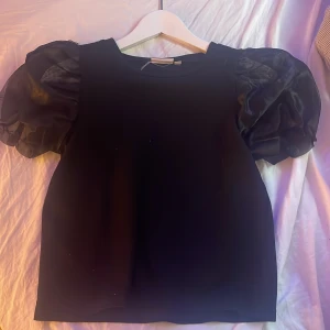 t-shirt  - medel tunt material, tunnare vid volangerna vid armen 