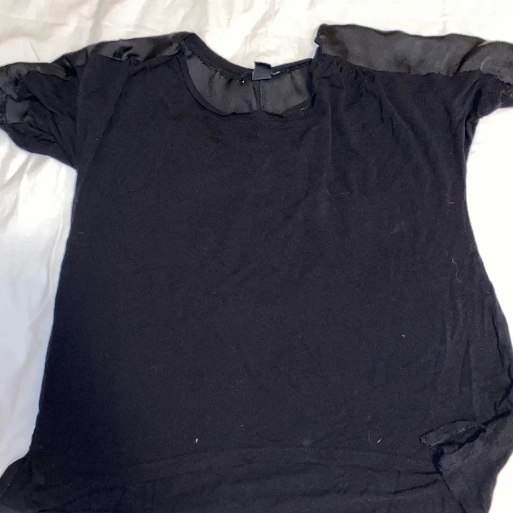 Säljer en svart T-shirt, vid axlarna har den som siden tyg.  Är från H&M och är i storlek M. OBS: köparen står för frakten. (Annonsen finns ute på fler sidor). T-shirts.