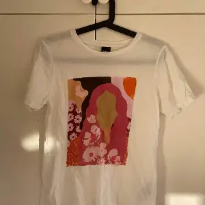 En t-shirt med färgglatt tryck av kvinna och blommor. bra skick. 
