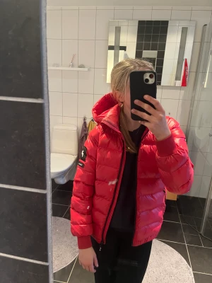 Peak performance jacka  - Röd skön vinter jacka ifrån peak performance. Köpes för 1899kr.  Detaljen på höger dragkedja har lossnat men funkar fortfarande fint, där av mitt pris. Jackan är i övrigt i ny skick! 