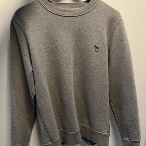 Paul Smith tröja - Säljer en väldigt snygg grå tröja från Paul Smith. Tröjan är i super bra skick och har inte använts många gånger! Bara höra av sig vid funderingar! Storlek: M Nypris: ca 1400 kr