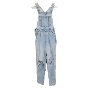 Hängselbyxor  - Ljusblå hängselbyxor där hålet på ena benet tyvärr slitit sig större åt ett håll (bild två) Därav det billiga priset