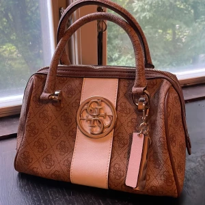 Guess väska - Snygg nästan oanvänd väska från Guess. Alla dragkedjor fungerar och mycket praktiska fickor