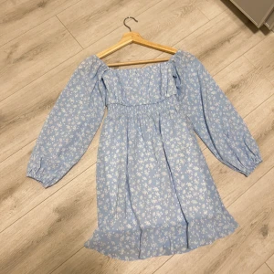 Klänning  - Ljusblått blommig klänning använt endast en gång. Kort över knäna