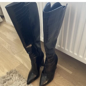 Svarta stövlar med klack  - Superfina svarta stövlar med klack. Storlek 38. Använd vid två tillfällen, så i princip som nya! osäker på märke men köpta från Zalando 