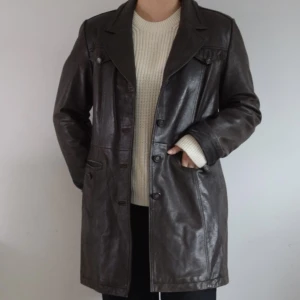 Vintage skinnjacka - Strl: M (uppskattad)  Mått: längd 81,5cm, ärmlängd innersöm 48cm Modell: figursydd, längre skinnjacka  Märke: Petroff Material: utsida 100% skinn, insida 100% polyester  Skick: använt skick, läder lite torrt på vissa ställen 