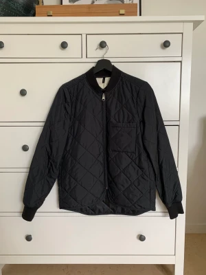 Quiltad jacka Arket stl 34 - Svart quiltad jacka från Arket. Storlek 34, normal i storleken. Använd men inget att anmärka på skicket. Perfekt höstjacka!   Hämtas i Uppsala eller skickas mot fraktkostnad