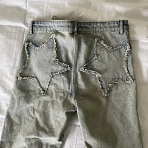 Bootcut jeans med stjärnor bak - Säljer dessa så najs bootcut jeansen från hm med coola stjärndetaljer bak. Storlek 40 men köpte i 2 storlekar större för att de skulle sitta lite mer baggy, så skulle säga passar 36/38. Helt nya, lappar kvar 