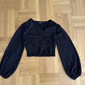 Blus från monki - Svart blus med vida armar och knappar vid bysten! 