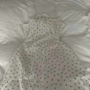 Blommig klänning  - Blommig kort klänning med snören i ryggen. Nyskick aldrig använd🌸