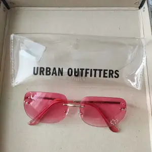 Rosa rimless solglasögon från Urban Outfitters. Strassdetalj i form av ett litet hjärta. Aldrig använda. Tillhörande fodral ingår.