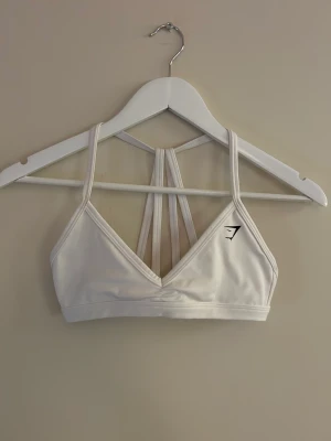 Gymshark sport-bh  - Vit sport bh från Gymshark. Använd en gång, nyskick. Nypris 300kr🤎köp fort☺️(för liten för mig)