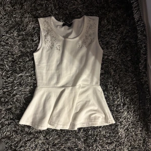 St topp med glitter ditaljer💓 - Det är en vit top med en volang vid botten och glittriga diamanter vid ärmarnaa.