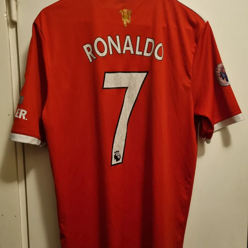 Fotbollströja real madrid med Ronaldos namn på ryggen. Lejon logga för Premier League . T-shirts.