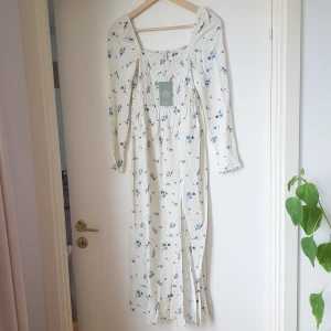 NY! Sommarklänning strl. XS - HELT NY! Med prislapp kvar. Sommarklänning, cottage core inspirerad, smockad överdel med fyrkantig halsringning. Slits i sidan. 100% viskos