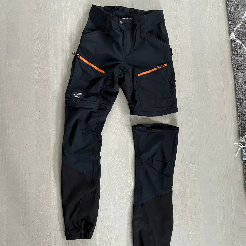 Silence zip off pants från Revolution Race i storlek 38/M. Man kan ta bort byxbenen med dragkedja och enkelt göra om dem till shorts. Längst ner finns även små hakar som gör att man kan fästa byxslutet på kängorna. Något tajta kring låren för storleken. . Jeans & Byxor.