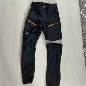 Silence zip off pants från Revolution Race i storlek 38/M. Man kan ta bort byxbenen med dragkedja och enkelt göra om dem till shorts. Längst ner finns även små hakar som gör att man kan fästa byxslutet på kängorna. Något tajta kring låren för storleken. 