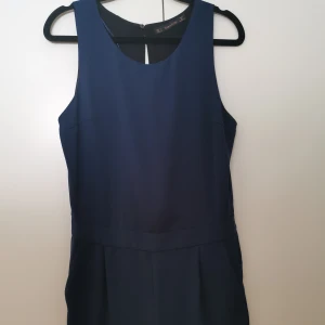 Mörkblå jumpsuit  - En snygg jumpsuit som är endast använd en gång till en fest. Den är i mycket fint skick, har öppen rygg och två gömda fickor.