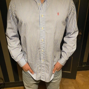 Ralph Lauren L - Blue striped Skjorta - Jättefin skjorta som man kan ha när man vill känna sig stilig. Modellen i bilden är 185Cm. Skjortan har använt en gång men säljer den för den är lite för stor och därför är den i nyskick. Original priset är 1795kr men säljer den bara för 399kr.