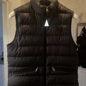Moncler TREOMPAN GILET  - Säljer nu min Moncler väst då jag är sugen på något nytt. Inköpt på Nordiska Kompaniet innan sommaren och är i väldigt bra skick! För fler frågor, tveka inte att höra av dig,, Mvh. Ludwig