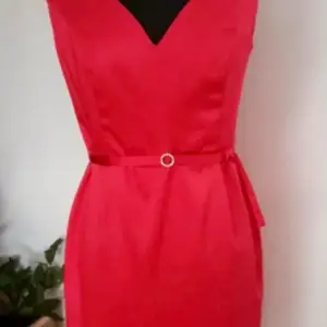 Röd klänning i glansigt, sidenliknande tyg med skärp i midjan. Storlek 40 (UK12). Stängs med dragkedja i bak.   Se även mina övriga annonser.