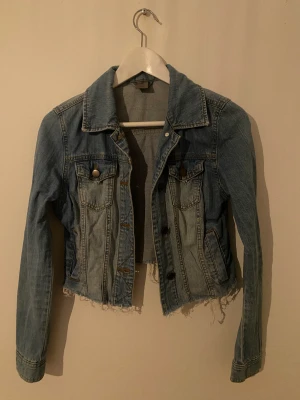 Jeansjacka  - Jeansjacka som jag har klippt av för att göra den kort. Vilket man ser på tredje bilden, att den är klippt. Går lätt att sy igen fickorna om man vill ha användning av dem. Storlek XS. Tror den är köpt på VILA. 