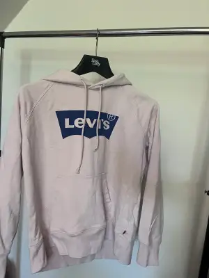 Levi’d hoodie i färgen ljusrosa och blå. Med luva och snöre. Den är inte använd så många gånger. Storlek M.