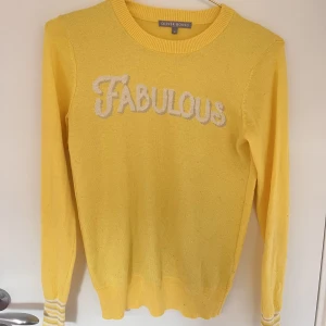 Ljusgul långärmad  - Ljusgul finstickad tröja med detaljer vid armarna samt med tryck på framsidan. 