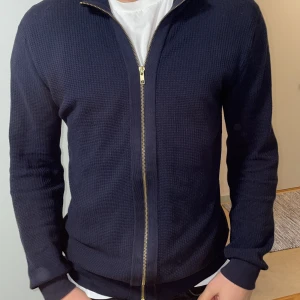 John henric fullzip tröja blå - John henric fullzip tröja i färgen blå med guldig zip, perfekt nu till hösten! Ny pris 1049kr.