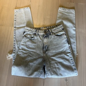 Gina Tricot jeans  - Ljusblåa mom jeans med hål på vardera knä från Gina Tricot i storlek 32. Högmidjade. Välanvända men i bra skick ändå! 70kr plus frakt. Har mycket fler plagg ute tillsalu! 