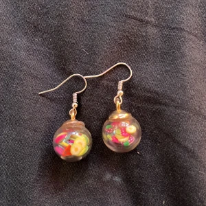 Örhängen med frukter i  - Bra skick, runda med frukter i, handgjorda och tog inte så lång tid att göra med ät lite jobbiga att göra