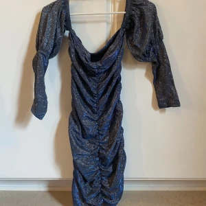 Kort glittrig festklänning  - Använt 2 ggr. Klänningen har väldigt mycket glitter på sig!!! Elastisk så passar bra till kroppen (tightform).