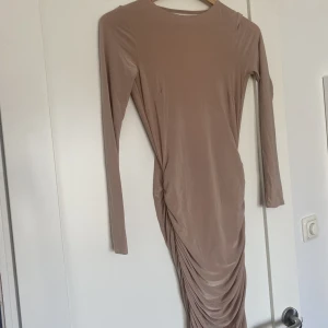 Nude klänning - Gammalrosa/nude tajt klänning i stretchiga matrial med öppen rygg och scrunchade ditaljer! Är lite ljusare irl