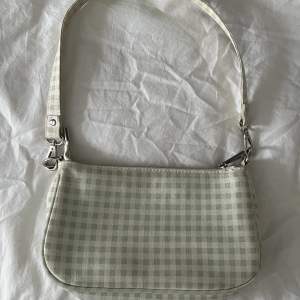 Jag säljer en gullig grön-vit rutig väska från Gina💗💗den är fint skick men är lite smutsig i axelbandet se bild 3💗Axelbandet är 49cm💗💗