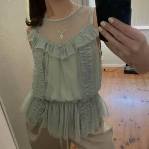As snygg topp  - Topp från H&M i en pastell grön färg. Toppen har volanger och är i ett mesh material. Den är i storlek 34 men skulle säga att den passar 36 utmärkt! 