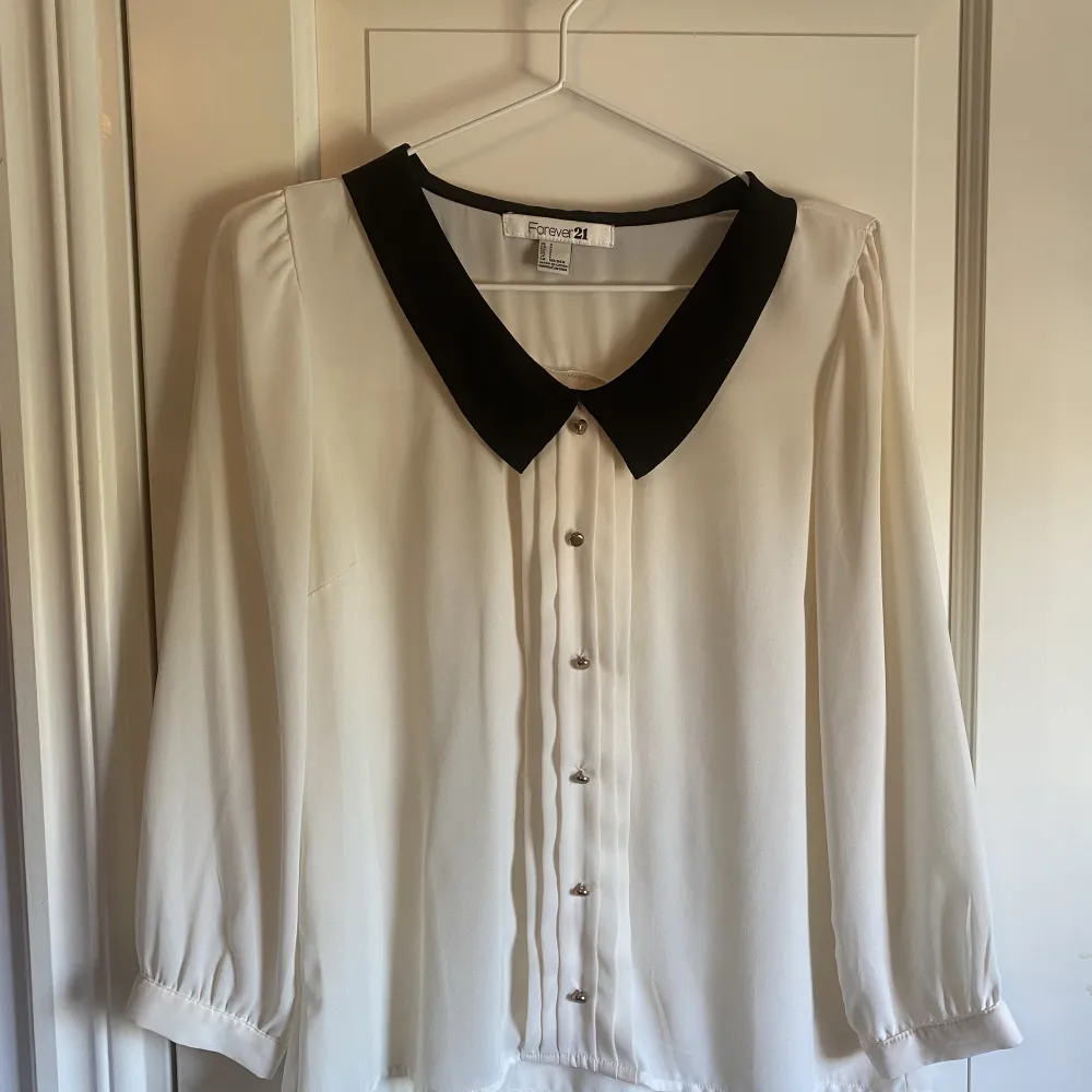 Vit blus med svart krage från Forever 21. Blusen har 3/4 ärmar och är i fint skick. Storlek S.. Puserot.