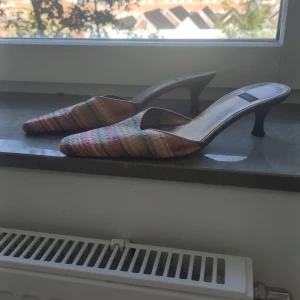 Spetsiga slipin-klackar  - Färgglada slipin-klackar med attityd! Spetsig tå och låg klack. Randigt, vävt material på ovansidan. Fina men med visst slitage (mest avskavd färg på innersulan som inte syns när man har dem på sig), därav lågt pris.