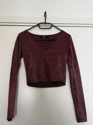 Glittrig crop top  - Glittrig v-ringad topp i mörkröd bråk bikbok Stl xs