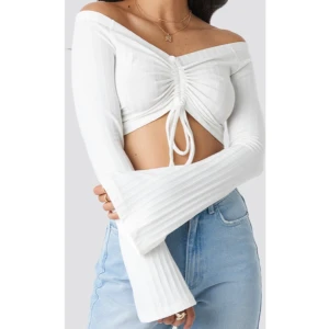 Off Shoulder Crop Top NA-KD x Adorable Caro - Ribbad långärmad croppad topp med vida ärmar och snörning framtill från NAKD x Adorable Caro. Storlek 38.  Oanvänd / Nytt skick!