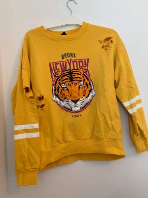Nästintill ny gul sweatshirt med häftigt tiger tryck och slitningar från Gina Tricot i storlek L.  Endast använd 1 gång.
