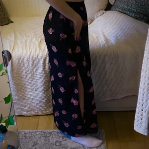 Blommig långkjol m slits - Svart långkjol med slits på båda sidorna, underkjol och i gott skick! Storlek M men vet inte var de är från. Har en likadan i olivgrön om du är intresserad!