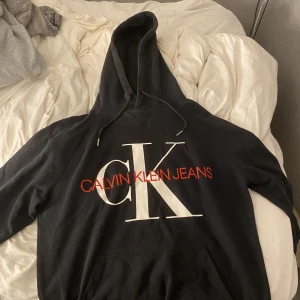 Calvin Klein Hoodie  - Svart Calvin Klein hoodie med röd text 6-7/10 i skick Fabriksfel på texten (på bild) kom från zalando