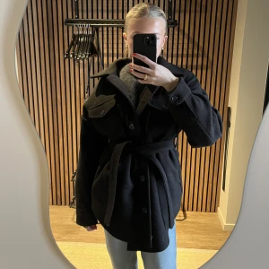 Jacka - Svart ”filt” jacka/kappa från Nelly💕 modellen är lite löbgre och har ett band man kan knyta i midjan