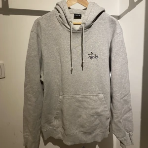 Grå Stüssy hoodie - Säljer en fet grå stussy hoodie i storlek L! Lite defekter på denna men det ger den lite karaktär enligt mig:) skriv för mer bilder om ni är intresserade🤙🏼