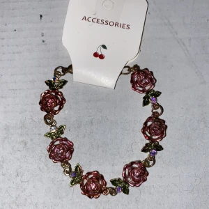 Armband  - Guldigt armband med ros detaljer.
