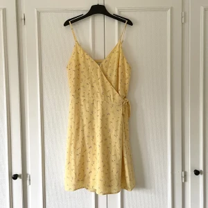 Hollister omlottklänning - Ljusgul omlottklänning med små blommor! Jättefin men används tyvärr inte längre. Väldigt fint skick!