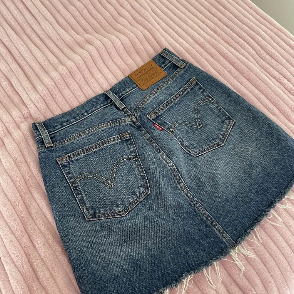 Jeanskjol som är köpt på Levi’s. Storleken är W25. Har lite fransar ner till. Kjolens längd är 37 cm. . Kjolar.