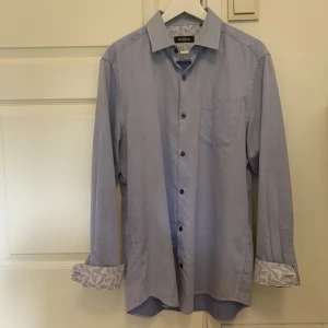 Ljusblå skjorta  - Ljusblå skjorta från Dressman. Storlek L (41/42). Väldigt bra skick, aldrig använd. Skicka meddelande vid frågor eller fler bilder 