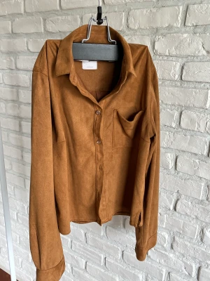 Subdued brun skjorta  - Vegan mocka skjorta, brun med knappar, liten ficka och krage. Inga skador.