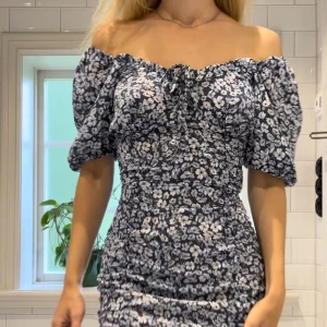 Fin blå klänning - Superfin blåblommig klänning. Kan användas med ärm eller off-shoulder. Lite puffiga armar, rynkad  i nederdelen och dold dragkedja i sidan. Använd 1 gång!🌸